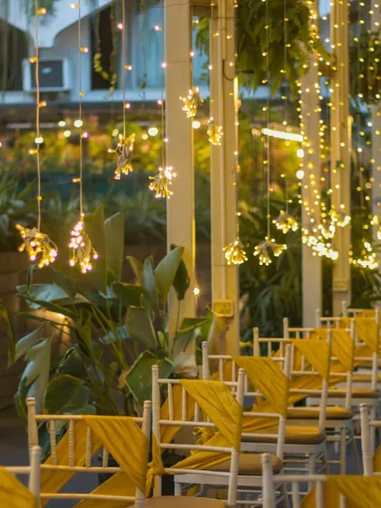 A close-up of the guest seating with yellow sashes, highlighting the elegant chairs and the warm glow of the fairy lights.