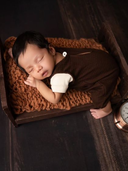 A simple and sweet pose of a newborn sleeping in a tiny wooden bed. The focus is entirely on the baby's serene and comfortable slumber.