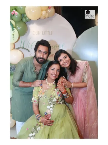A happy family portrait with the parents-to-be and a sibling, all smiles in front of the beautiful event decor.