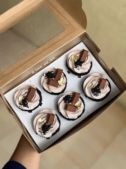 A box of delicious KitKat-topped cupcakes with a touch of edible gold leaf for elegance.