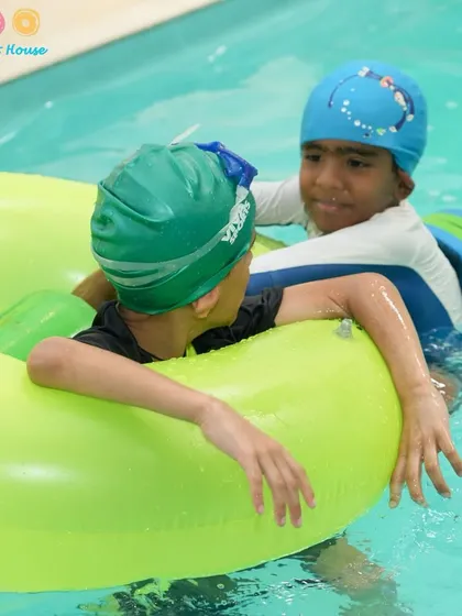Friends helping each other out with a floatie. Our classes encourage teamwork and support among students, creating a positive learning environment.