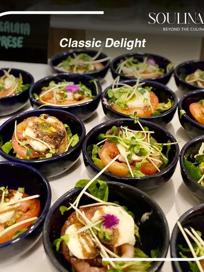 A classic Caprese salad presented in individual bowls, garnished with microgreens and edible flowers. A timeless delight, elevated with our signature touch.