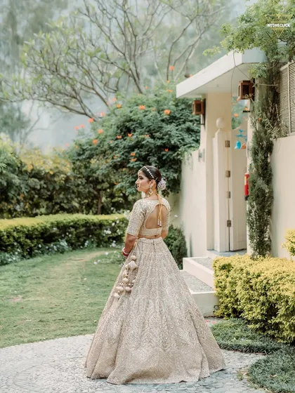 A beautiful back-shot of the bride in her elegant pastel lehenga, showing off the intricate details of her outfit and hairstyle.
