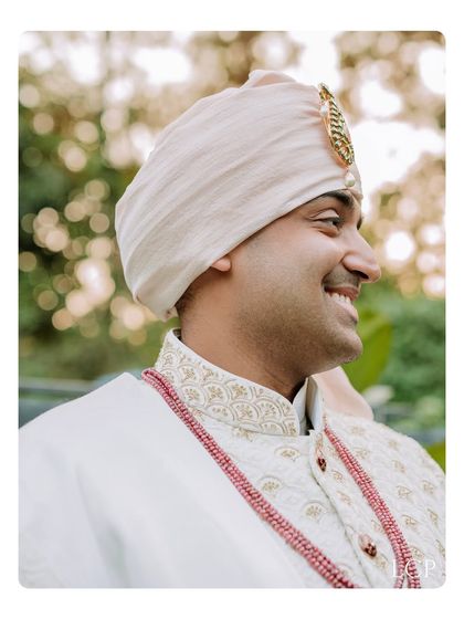 A candid, smiling profile of the groom in his wedding attire, capturing a moment of pure happiness.