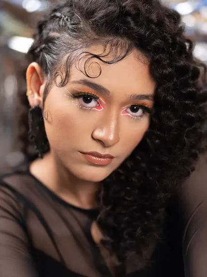 The art of eye contact. This editorial look features a neon graphic liner on a curly-haired model, creating a modern, edgy, and high-fashion aesthetic.