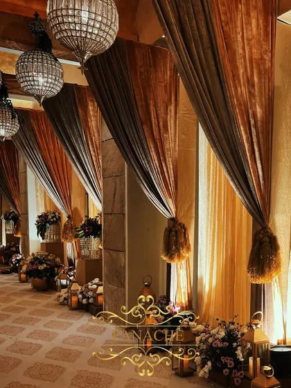 A side view of the draped corridor, showing the rich texture of the fabrics and the warm glow of the lighting. The tassel tie-backs add a touch of classic elegance to the decor.
