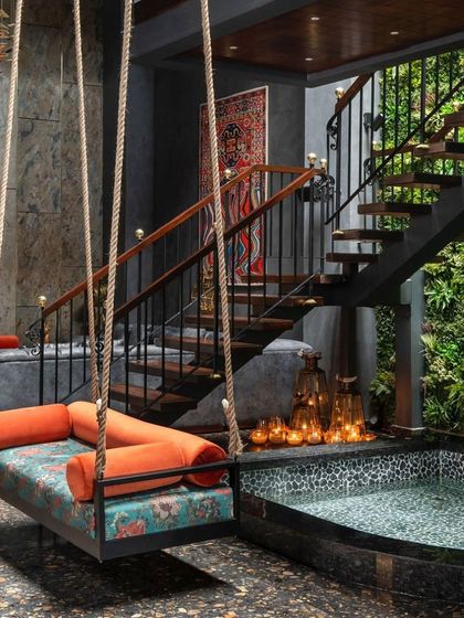 A custom swing suspended over a tranquil water body in the Utopia residence. This feature, set against a dramatic stone wall and adjacent to the vertical garden, creates a multi-sensory experience that is both playful and deeply calming.