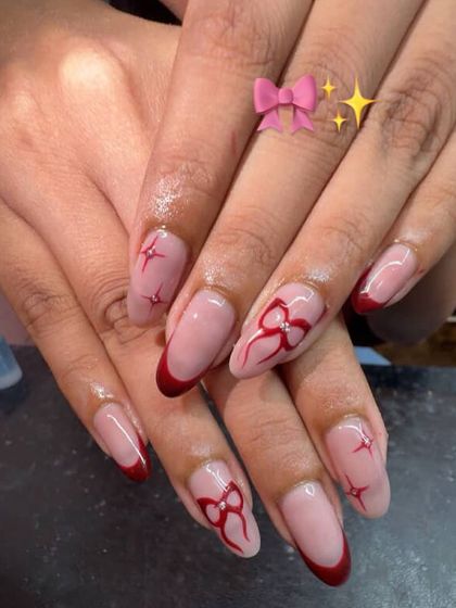 A red French manicure with hand-painted red bows and starbursts.