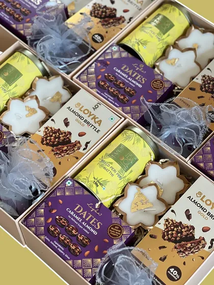 A bird's-eye view of our premium Diwali gift boxes, ready for a bulk order. Each one is packed with almond brittle, caramel dates, star-shaped cookies, and other festive snacks.