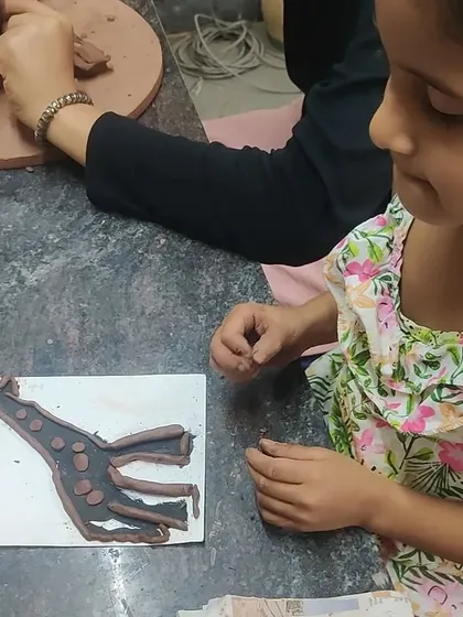 A young artist works on a clay giraffe silhouette. This activity helps children think about shapes and unique features while developing their fine motor skills.
