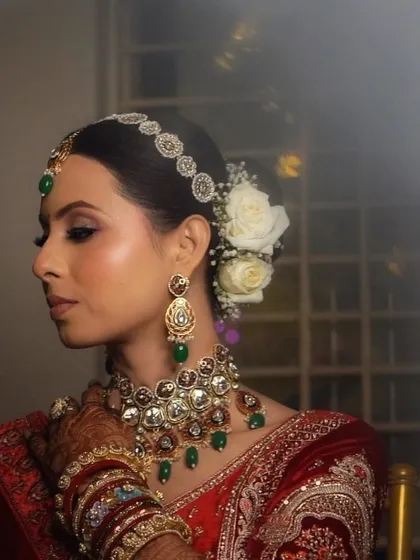 Another stunning profile shot, this time focusing on the elegant bun with white roses and the heavy bridal jewelry.