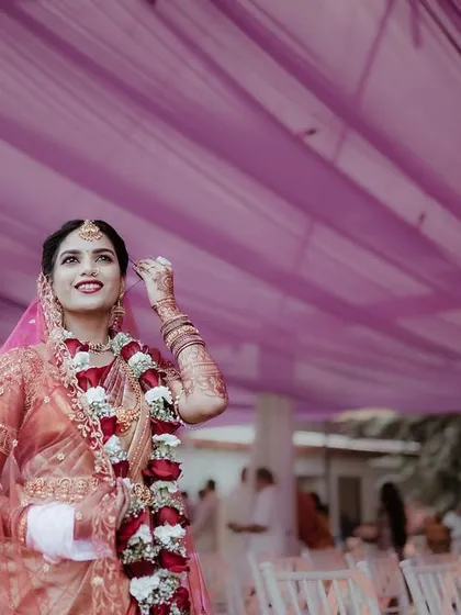 A low angle shot of the bride looking up, with the purple fabric of the mandap creating a beautiful frame. This photo highlights her joy and the festive wedding decor.