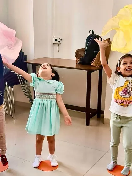 Three girls express their joy with colorful scarves during a movement exercise. Music education is about fostering creativity and emotional expression.
