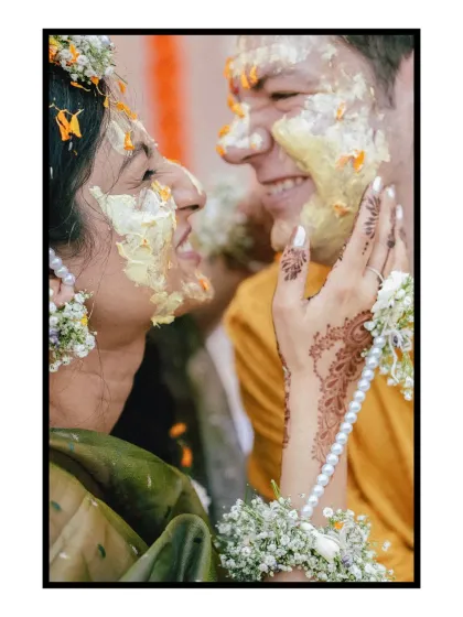 A close-up of pure Haldi happiness. The laughter is infectious as the couple playfully applies turmeric paste to each other, their faces lit up with joy. This is the candid, messy, beautiful reality of an Indian wedding.