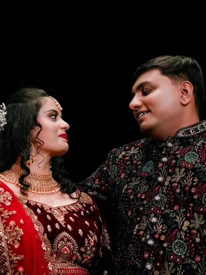 A romantic gaze between the couple, captured against a dark background to emphasize their connection.