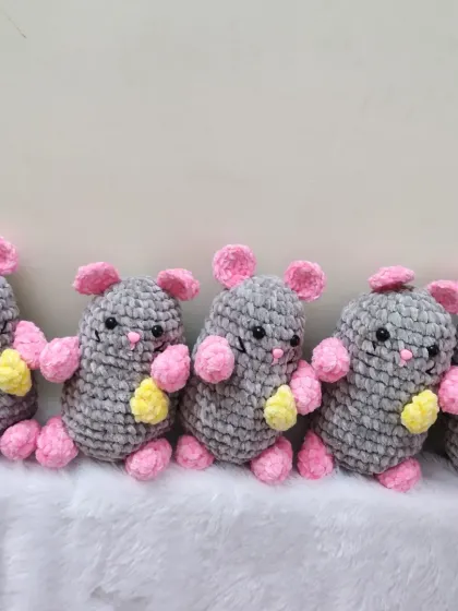 A lineup of my cute crochet rat soft toys. Made with chunky gray and pink yarn, each one is holding a little piece of cheese.