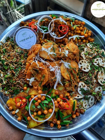 This is a perfect platter for an evening party, featuring a mix of my most popular snacks. It includes spicy 'Singju' salad, crispy 'Bora' fritters, 'Kelichana' (spicy chickpeas), and an 'aloo' mixture.