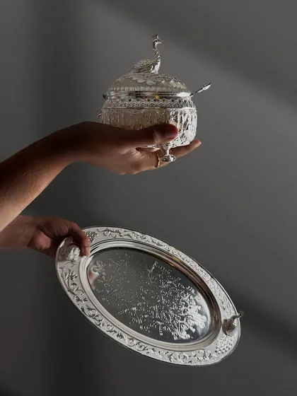 The art of balance. This image captures the elegant interplay between a finely engraved silver tray and a matching lidded box, showcasing how simple white enamel can create a sophisticated look.