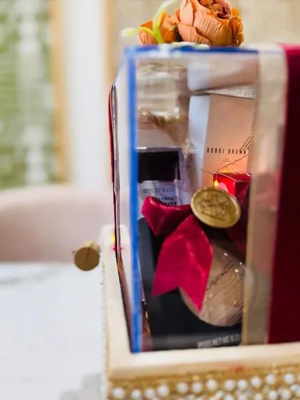 A side view showing the layers of gifts inside the acrylic box, wrapped in velvet ribbon and illuminated by fairy lights.
