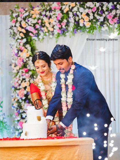 The cake-cutting ceremony at an engagement, with the couple framed by a lovely arch of pastel-colored flowers.