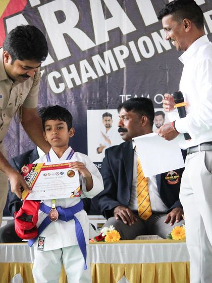 A young champion receives his medal and certificate at our inter-school karate championship. We believe in recognizing effort and achievement to motivate our students on their martial arts journey.