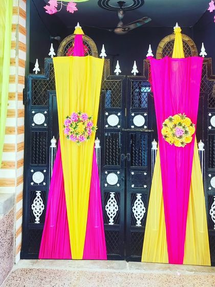A symmetrical gate decoration with pink and yellow drapes, creating an elegant and balanced look for the main entrance.