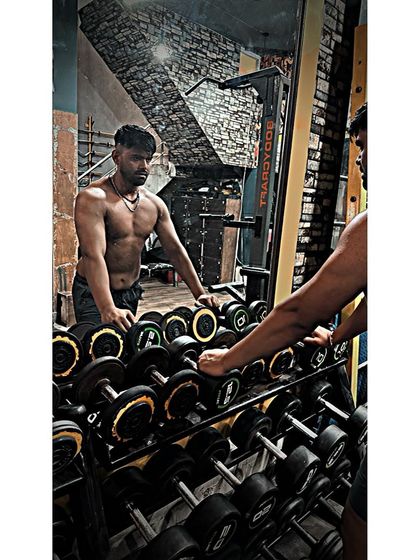 Pausing by the dumbbell rack. The gym is my second home, the place where I forge my strength.