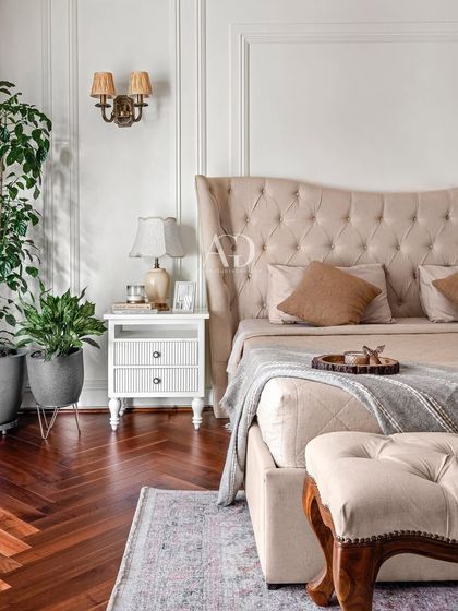 A close-up detail of the bedside, showing the classic white nightstand and elegant wall sconce. I believe in incorporating every little detail to match the client's taste and transform a house into a home.