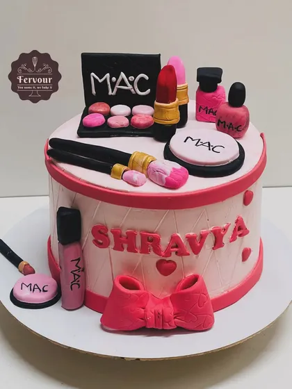 A makeup theme cake featuring MAC products. This cake is decorated with all-edible fondant lipsticks, palettes, brushes, and powders, perfect for a makeup lover.