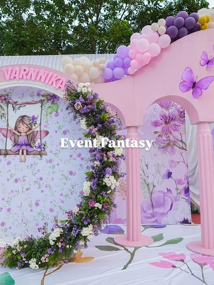 A unique photo opportunity prop at Varnnika's party, featuring a floral-wreathed circular frame with a fairy illustration.