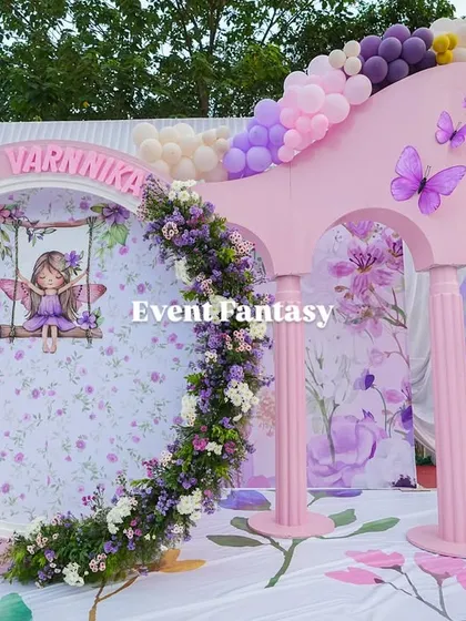 A unique photo opportunity prop at Varnnika's party, featuring a floral-wreathed circular frame with a fairy illustration.