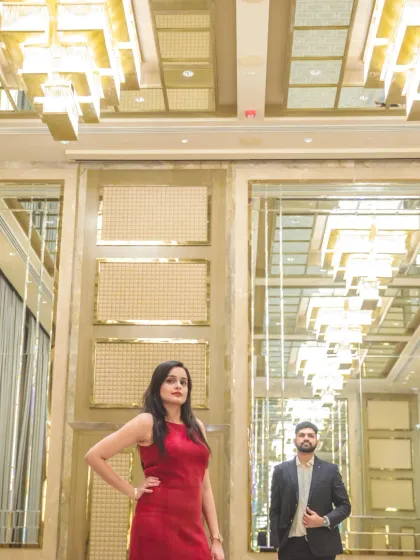 A creative, low-angle shot in a modern, luxurious hall. The mirrored ceiling and geometric lights create a unique and glamorous backdrop for the couple.