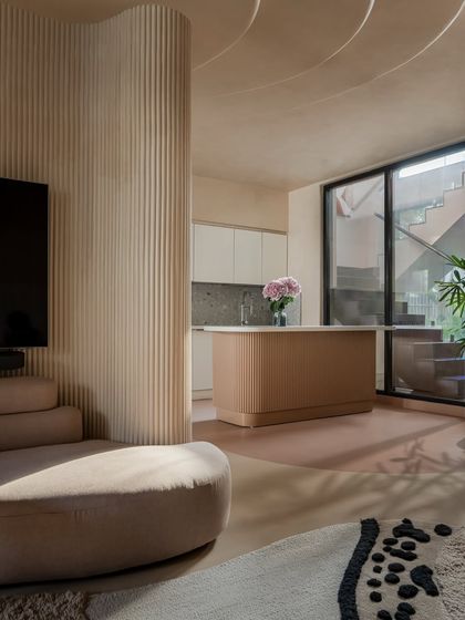 A wider view of the kitchen and living area, showing how the curved column and ceiling detail unify the open-plan space. The design allows for easy movement and visual connection between zones.