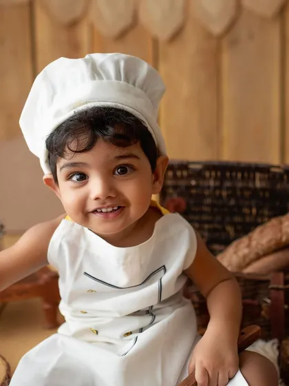 A close-up of my little chef. His happy expression and the adorable uniform make this a picture-perfect moment.
