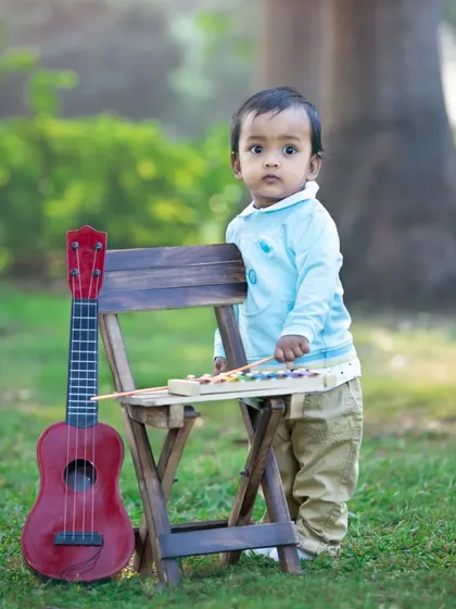 A toddler stands with his guitar and xylophone, ready to make some music.