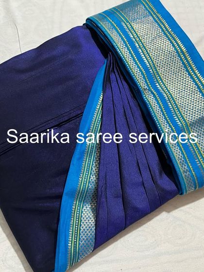A simple navy blue saree with a light blue border, pleated for a clean, elegant look. Ideal for formal events.