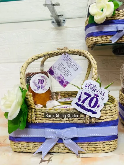 The details of the 70th birthday hamper, including a personalized card and a dry cake, all tied together with a lavender ribbon.