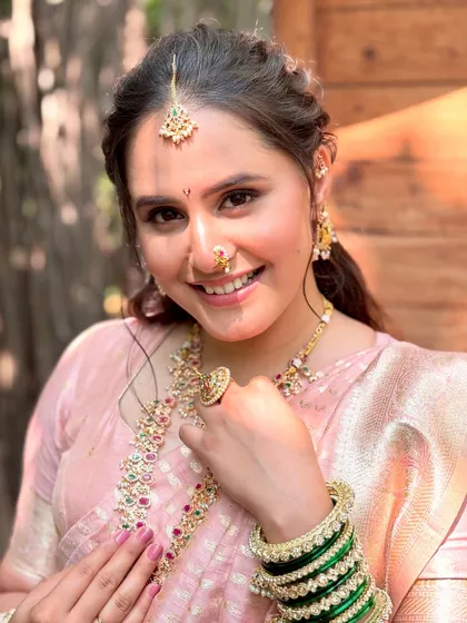 A beautiful close-up showcasing the flawless skin finish and the traditional bindi and nath. The soft pink eyeshadow and lip color bring a gentle warmth to the entire look.