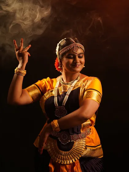 A close-up of the Bharatanatyam dancer, showcasing the detailed temple jewelry, headpiece, and expressive face.