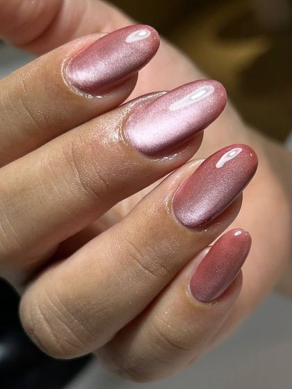 A beautiful rose-gold cat-eye manicure on oval-shaped nails. The warm, shimmery tones are both elegant and on-trend.