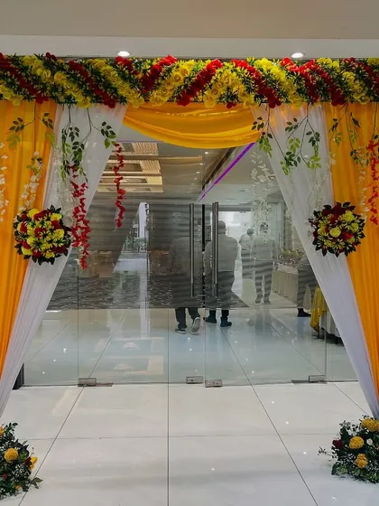 A classic entrance arch for a banquet hall, decorated with yellow and red flowers and yellow and white drapes.