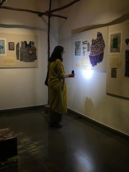Artist Pushpamala N visiting 'WEAVING LIGHT' and using a flashlight to see the details.