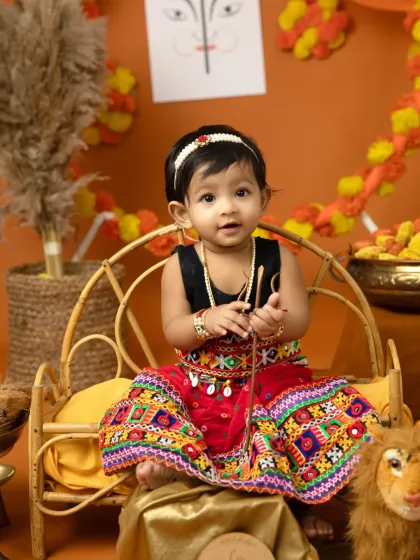 Holding a tiny bow and arrow, this little girl is ready for Dussehra. These themed props add a playful and meaningful element to the photos.