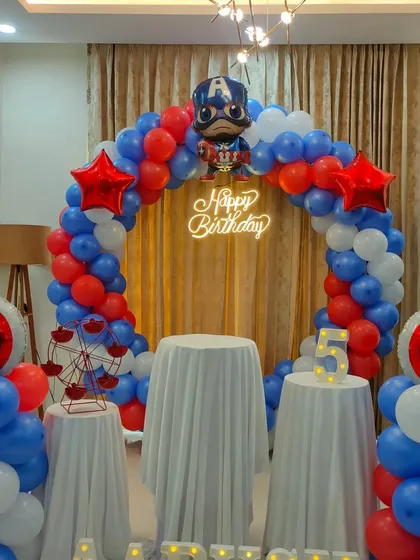 A Captain America superhero theme with a red, white, and blue balloon arch. The setup includes themed props like the hero's shield and a character foil balloon.