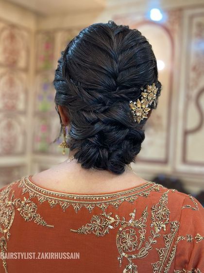 The same braided low bun as in image 19, but this time adorned with a beautiful gold floral clip. This shows how a simple accessory can elevate the entire look.