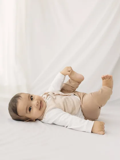 A simple, beautiful portrait of the baby lying on a clean white background, capturing his happy-go-lucky nature.