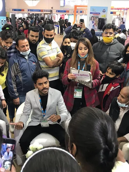 Explaining a trick to an engaged audience, holding their attention while they are surrounded by the company's branding.