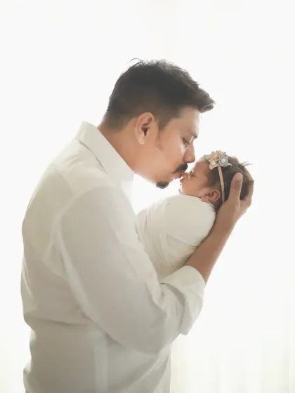 A silhouette of a father's love. The high-key lighting creates a beautiful, angelic feel for this newborn portrait.