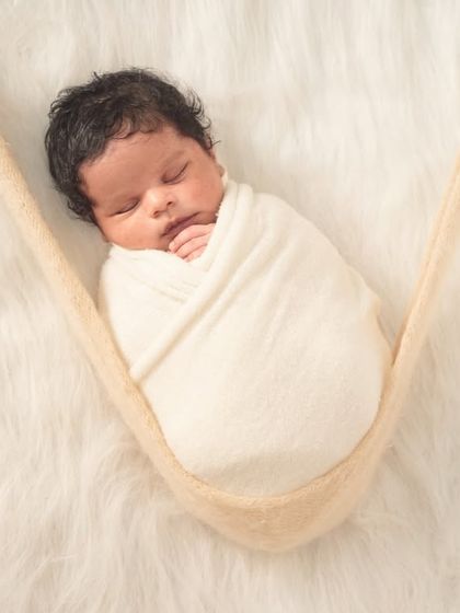 Gently suspended in a soft sling, this swaddled baby looks like they're floating on a cloud. This is one of my favorite poses for showing how tiny they are.