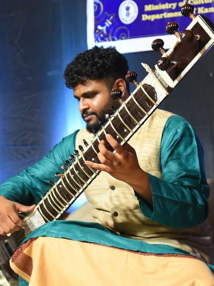 Playing a deep phrase during a raga presentation. My traditional attire, a kurta and vest, is typical for a classical Indian music concert.